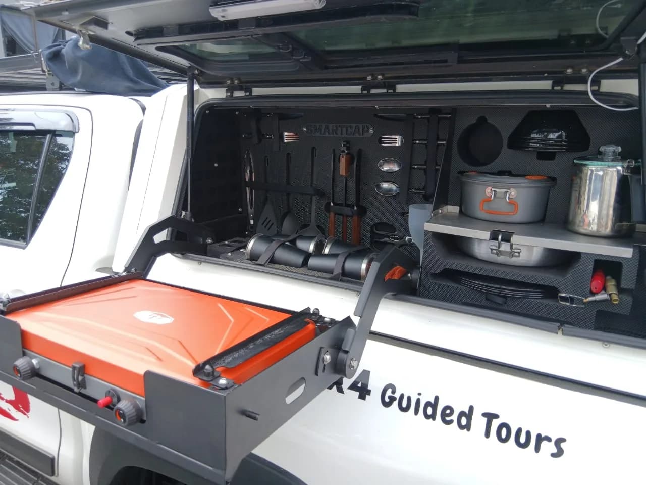 The slide-out camp kitchen: gas cooker, full cook set and utensils stowed in the canopy